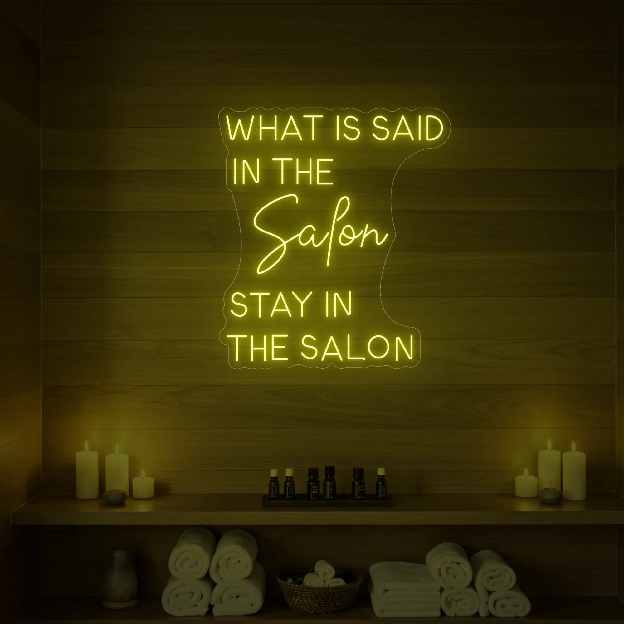 Photo of the 'WHAT IS SAID IN THE SALON STAY IN THE SALON' neon sign glowing in lemon yellow against a styled interior wall.