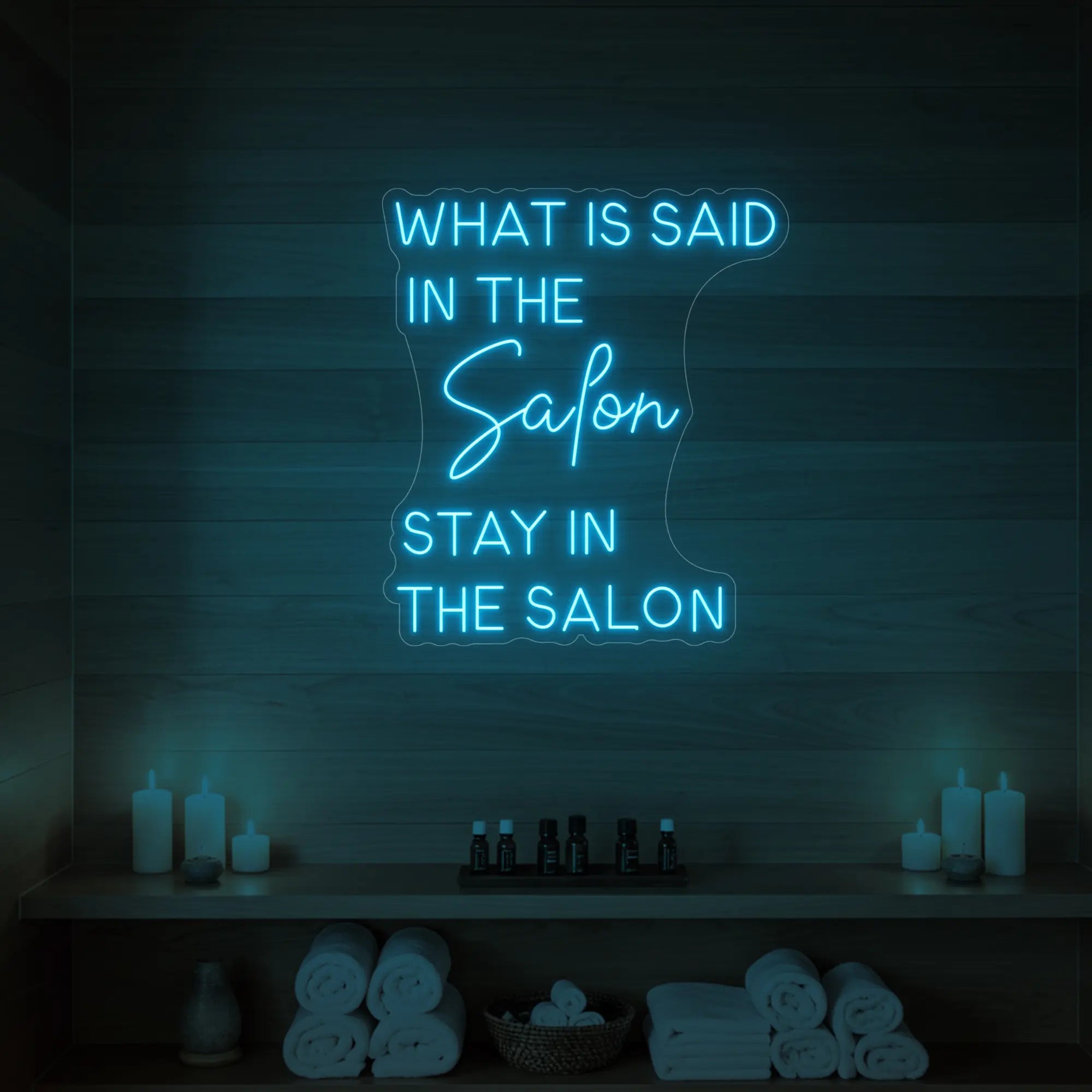 Photo of the 'WHAT IS SAID IN THE SALON STAY IN THE SALON' neon sign glowing in ice blue against a styled interior wall.