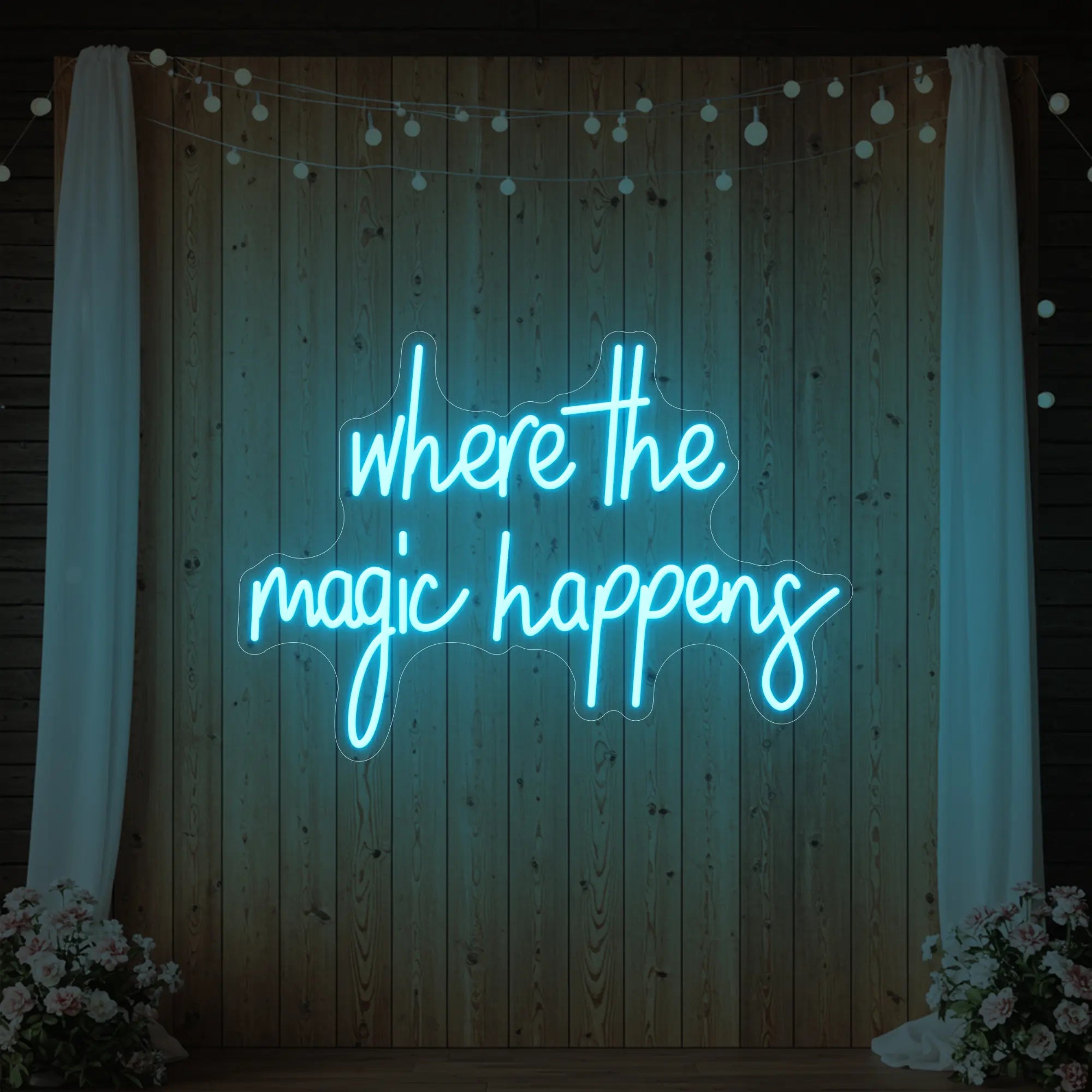 'Where The Magic Happens' neon sign glowing in ice blue against a styled interior wall.