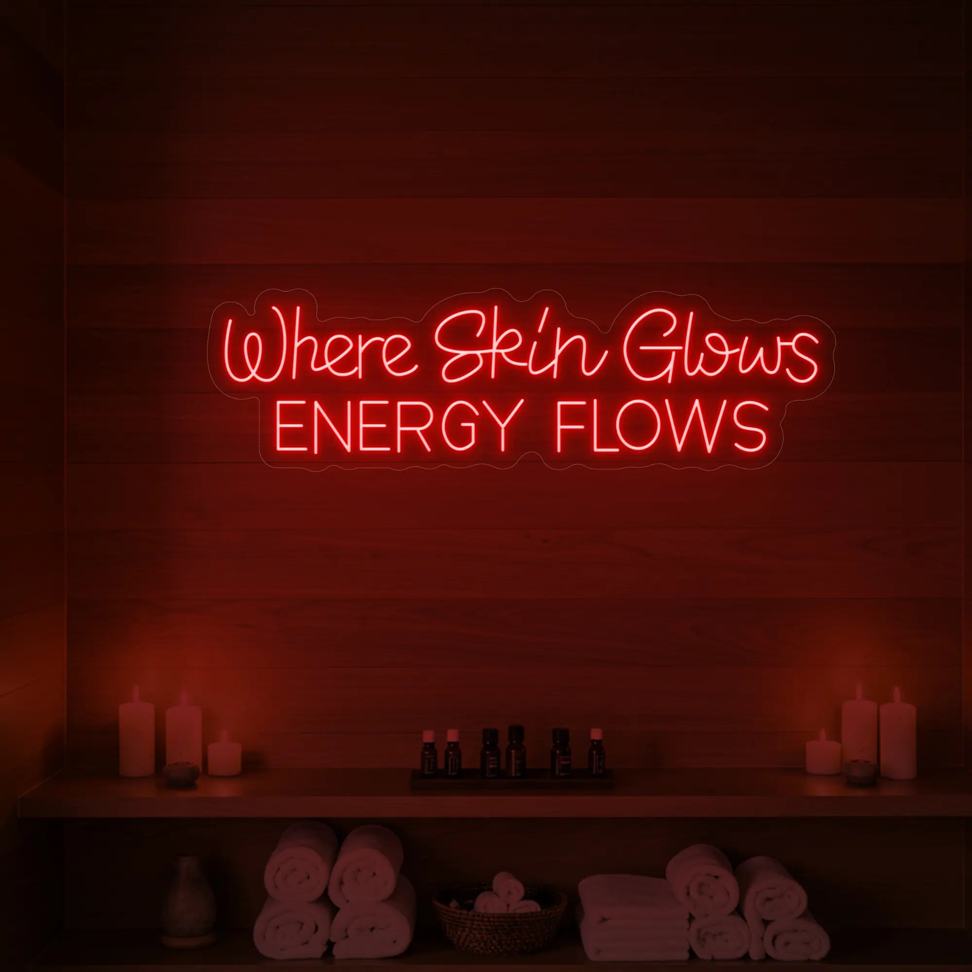 Photo of the 'Where Skin Glows, Energy Flows' neon sign glowing in red against a styled interior wall.