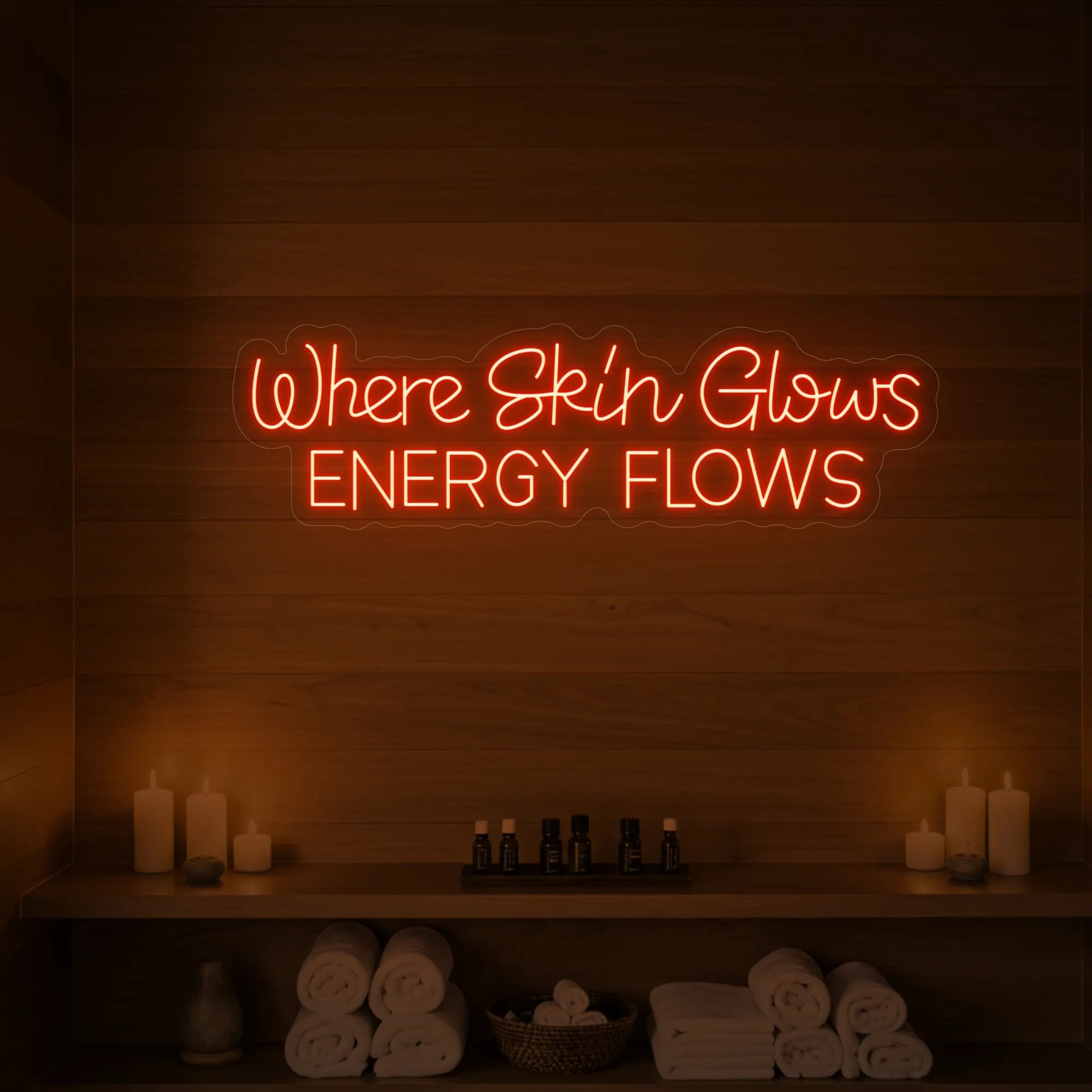 Photo of the 'Where Skin Glows, Energy Flows' neon sign glowing in golden yellow against a styled interior wall.