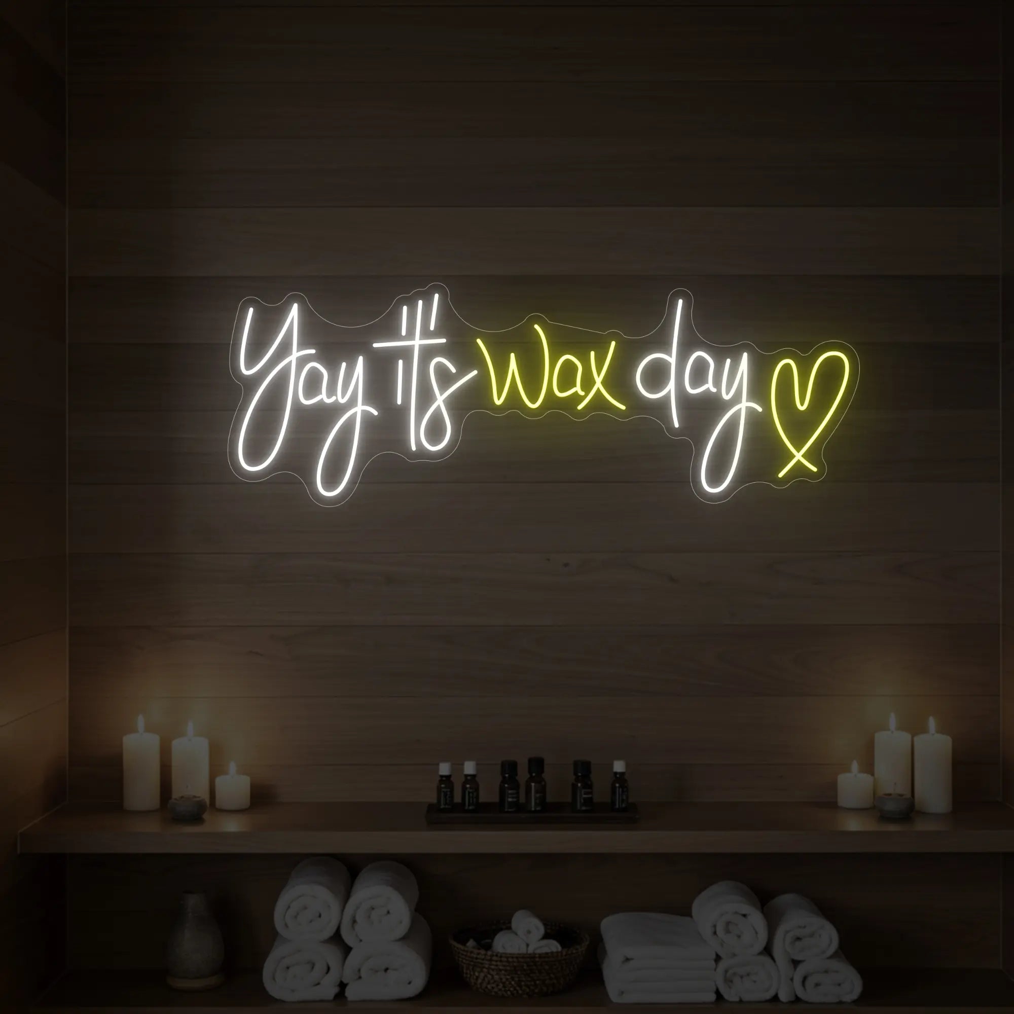 Photo of the 'Yay It’s Wax Day ❤' neon sign glowing in lemon yellow against a styled interior wall.