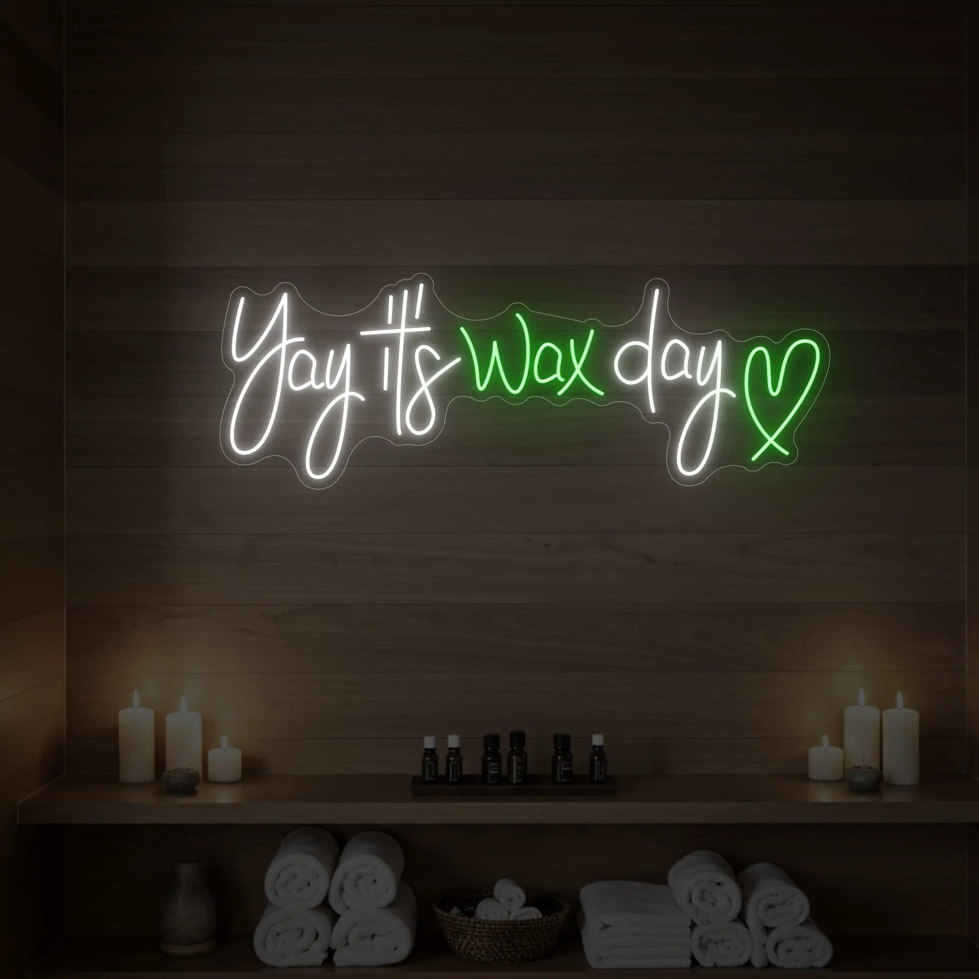 Photo of the 'Yay It’s Wax Day ❤' neon sign glowing in green against a styled interior wall.