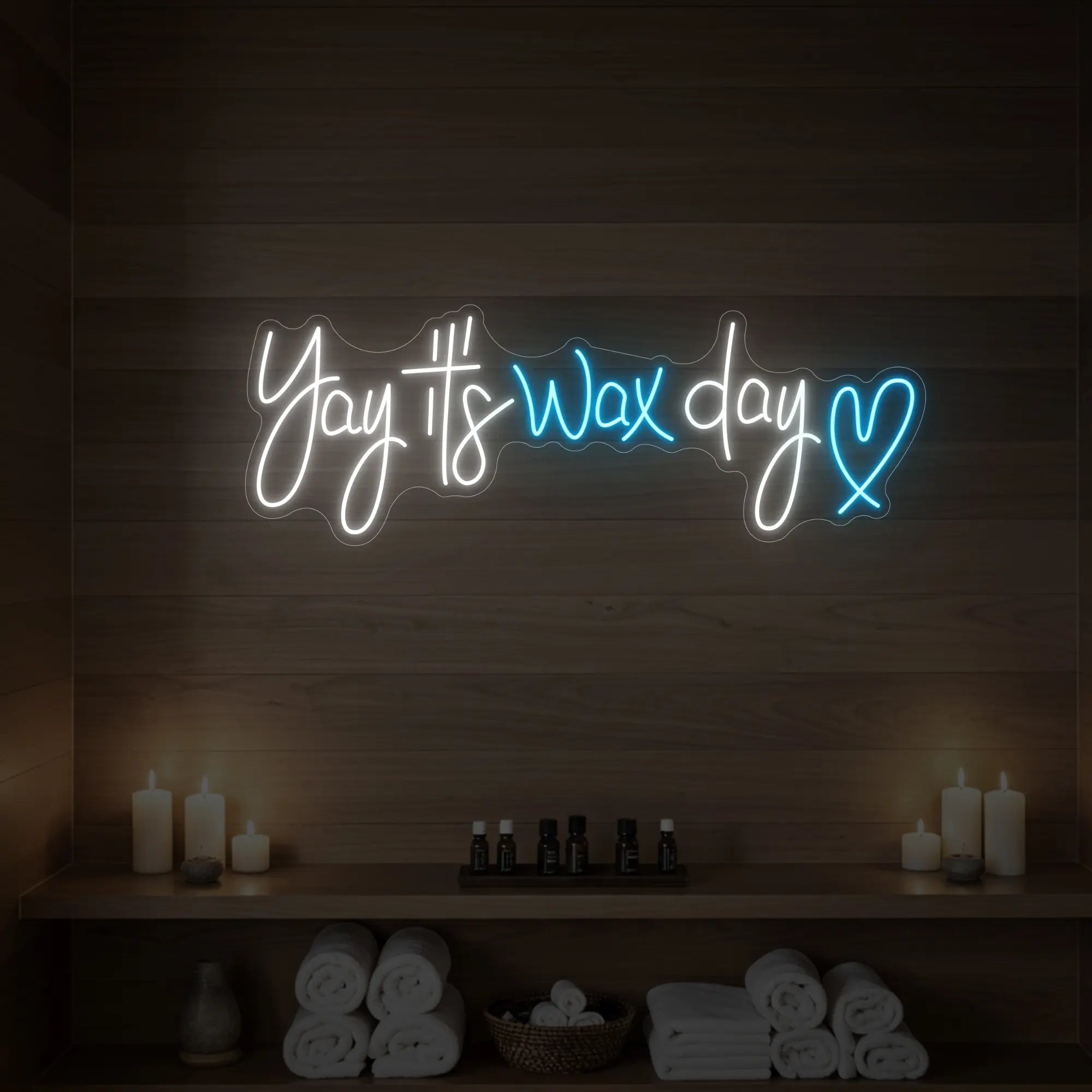 Photo of the 'Yay It’s Wax Day ❤' neon sign glowing in ice blue against a styled interior wall.