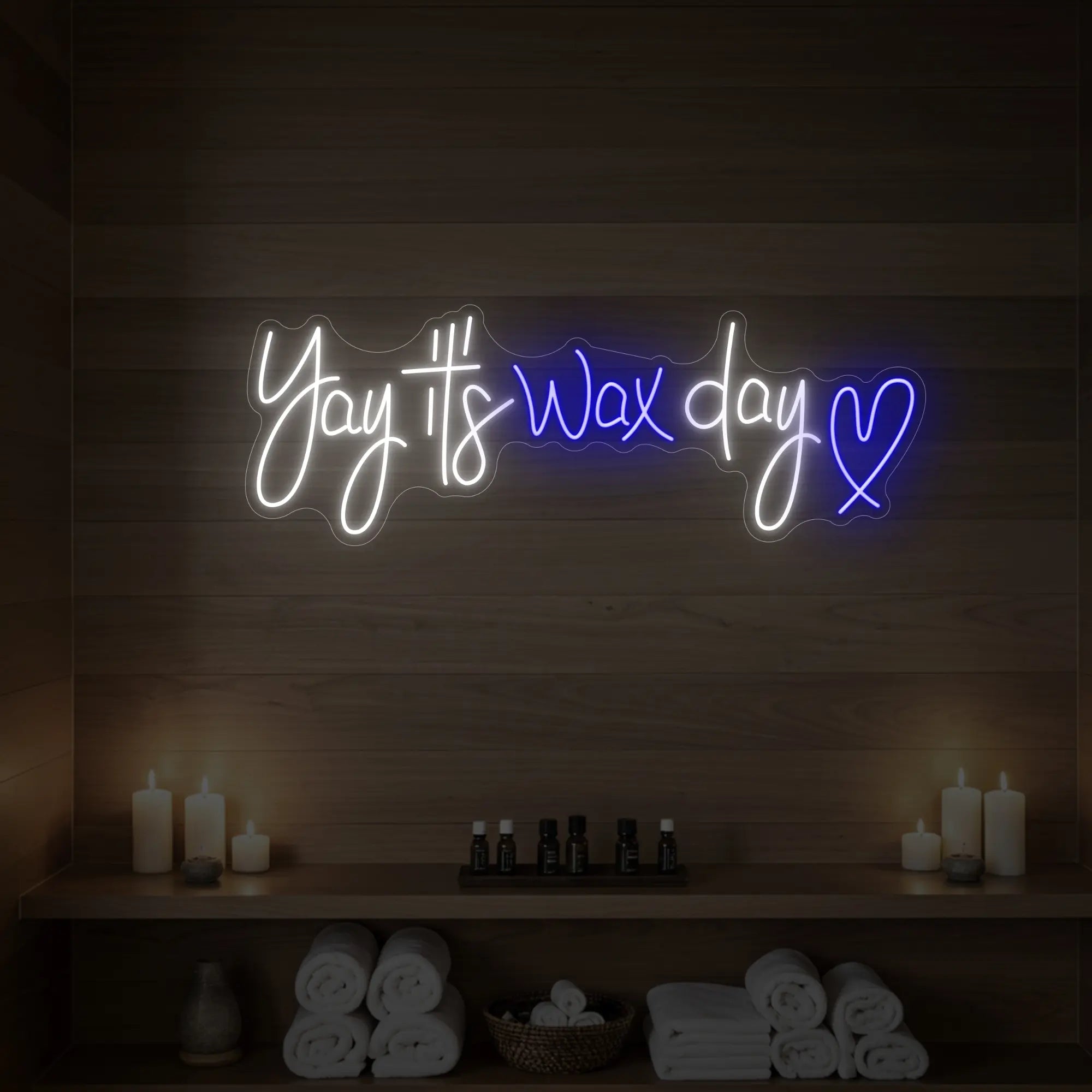 Photo of the 'Yay It’s Wax Day ❤' neon sign glowing in deep blue against a styled interior wall.