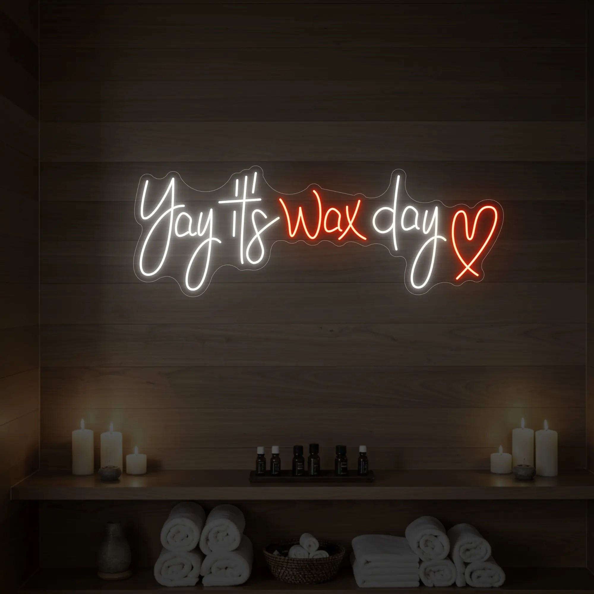 Photo of the 'Yay It’s Wax Day ❤' neon sign glowing in golden yellow against a styled interior wall.