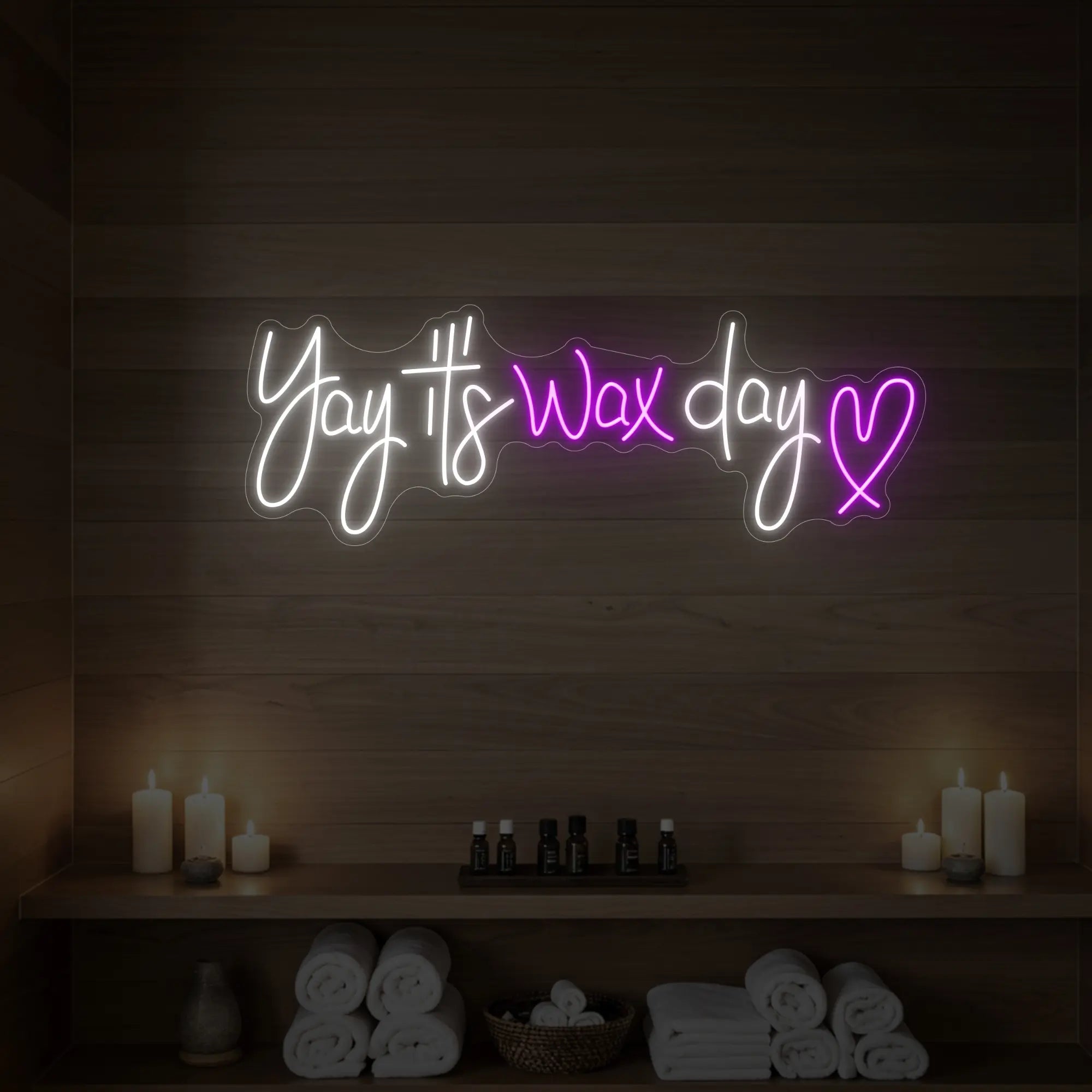 Photo of the 'Yay It’s Wax Day ❤' neon sign glowing in deep pink against a styled interior wall.