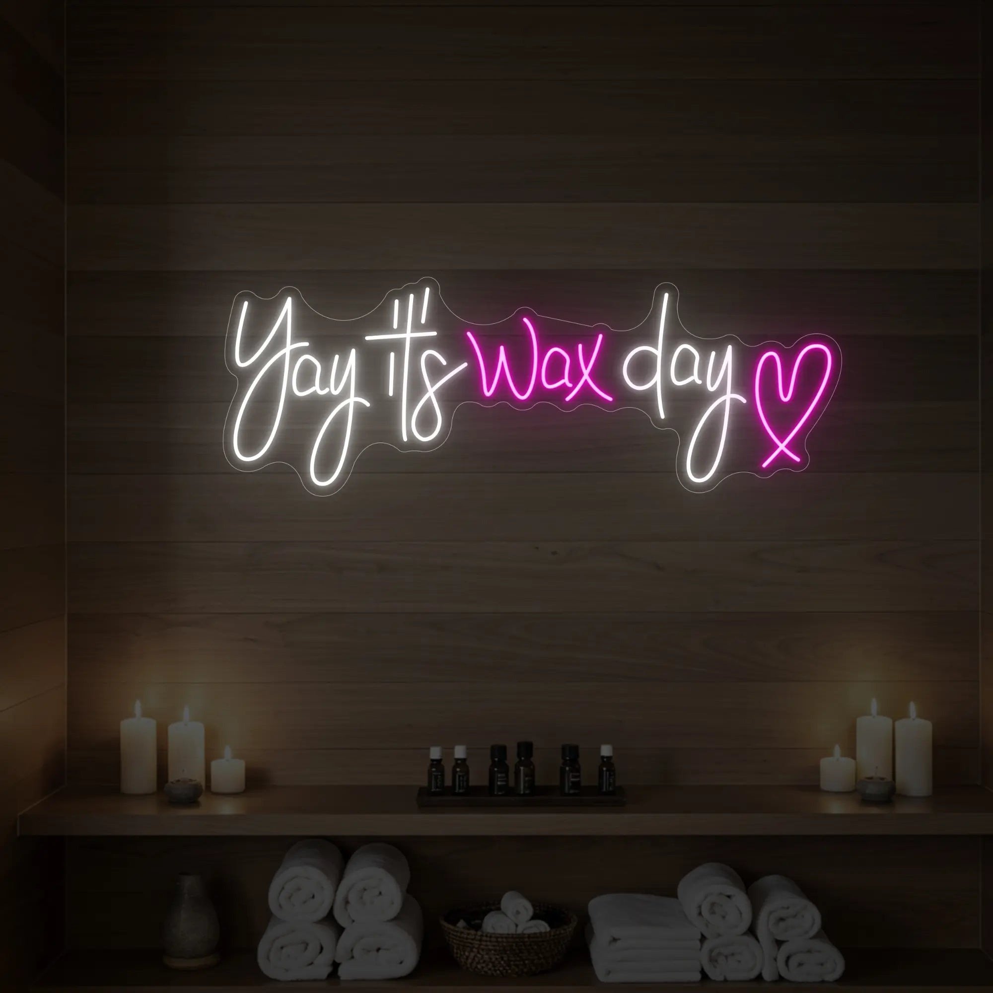 Photo of the 'Yay It’s Wax Day ❤' neon sign glowing in light pink against a styled interior wall.