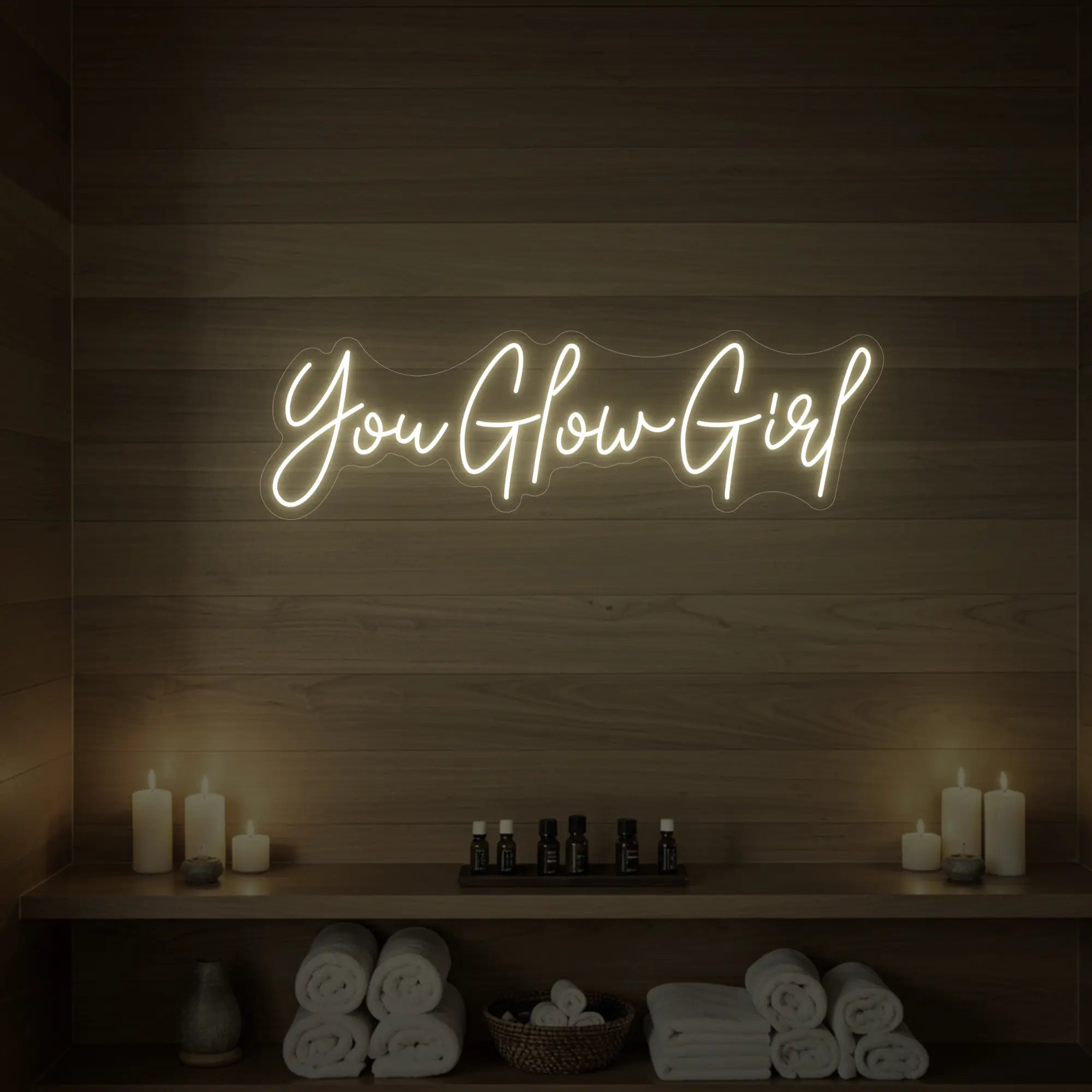 Photo of the 'You Glow Girl' neon sign glowing in warm white against a styled interior wall.