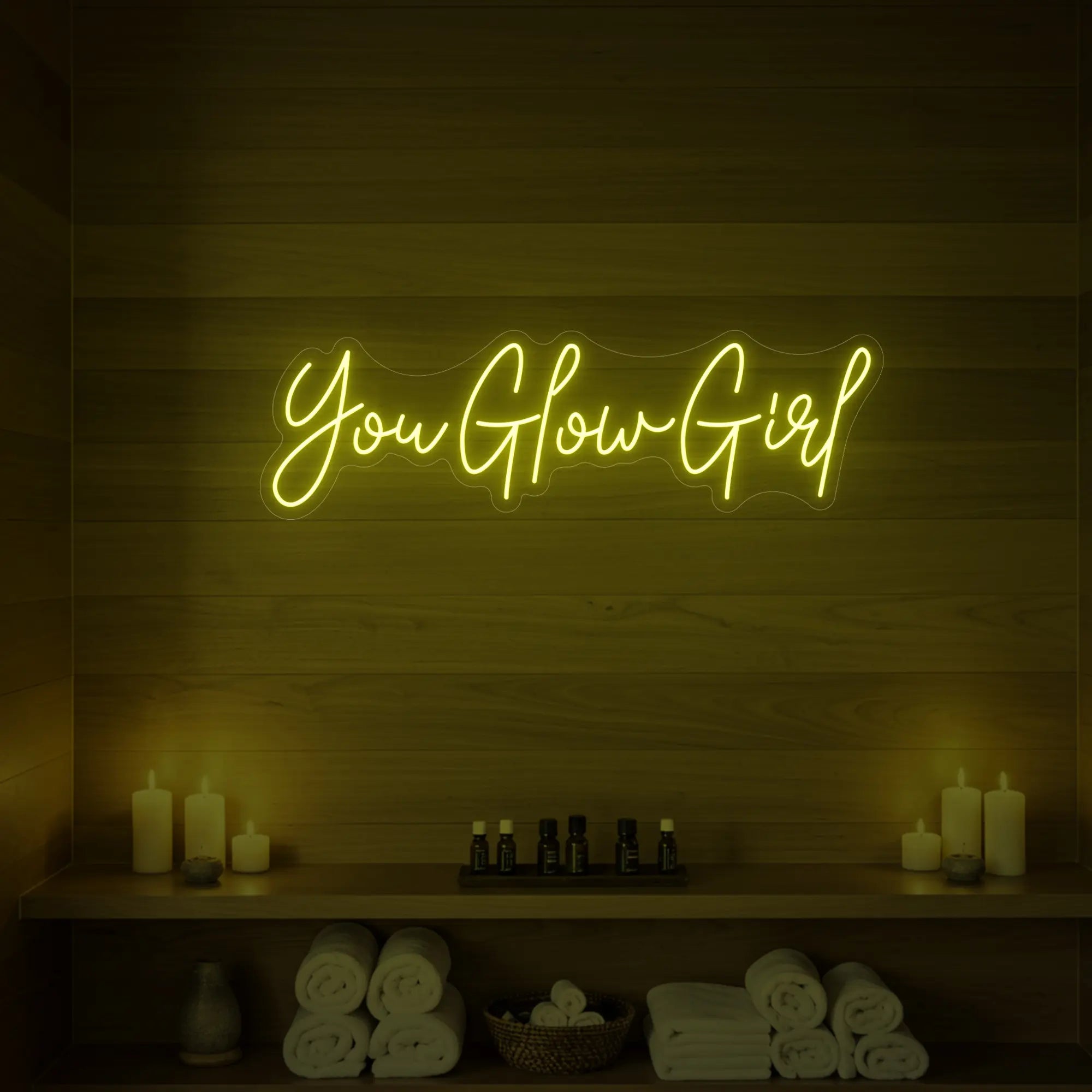 Photo of the 'You Glow Girl' neon sign glowing in lemon yellow against a styled interior wall.