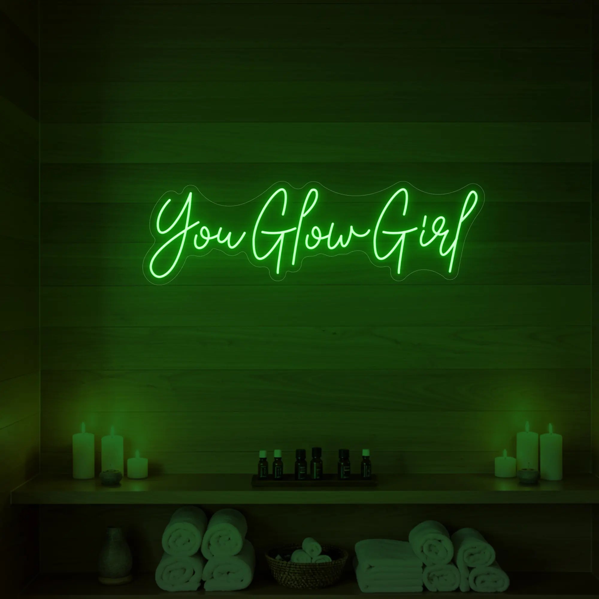 Photo of the 'You Glow Girl' neon sign glowing in green against a styled interior wall.