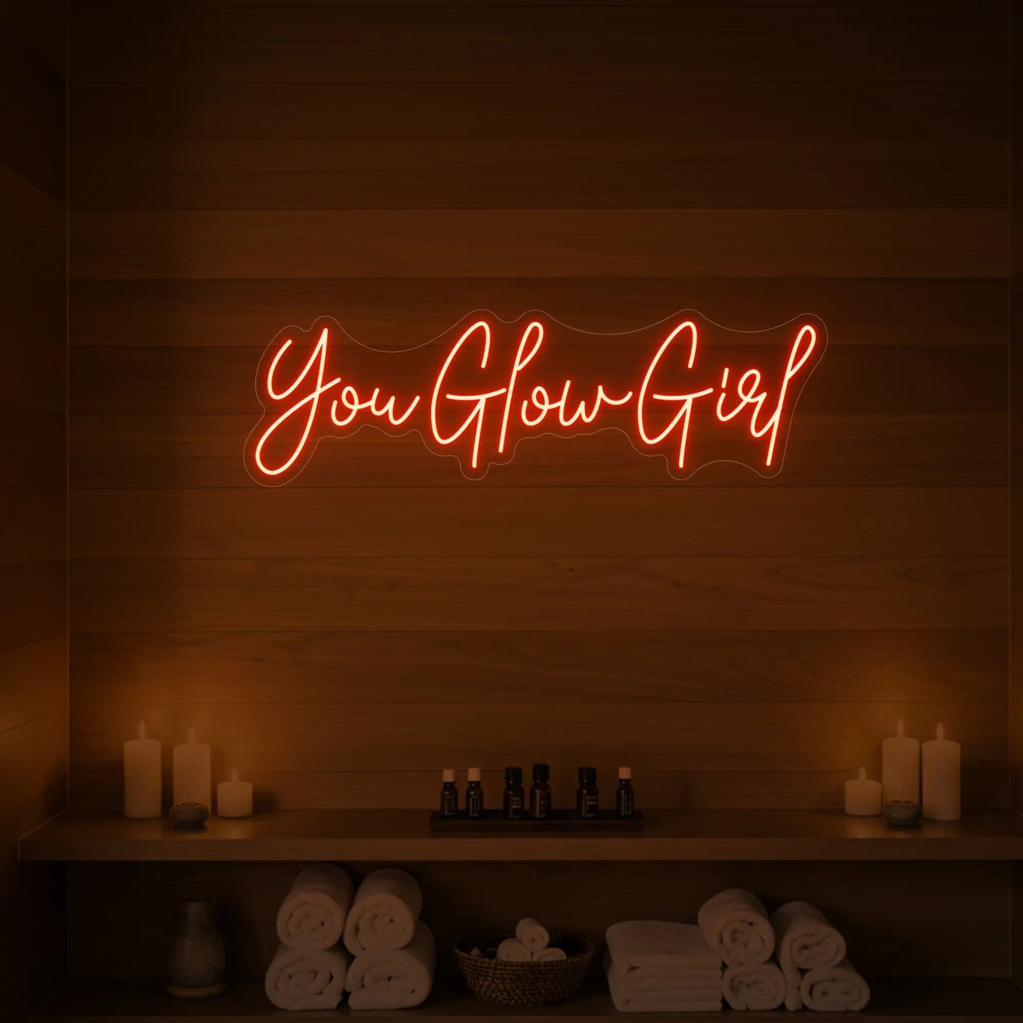 Photo of the 'You Glow Girl' neon sign glowing in golden yellow against a styled interior wall.