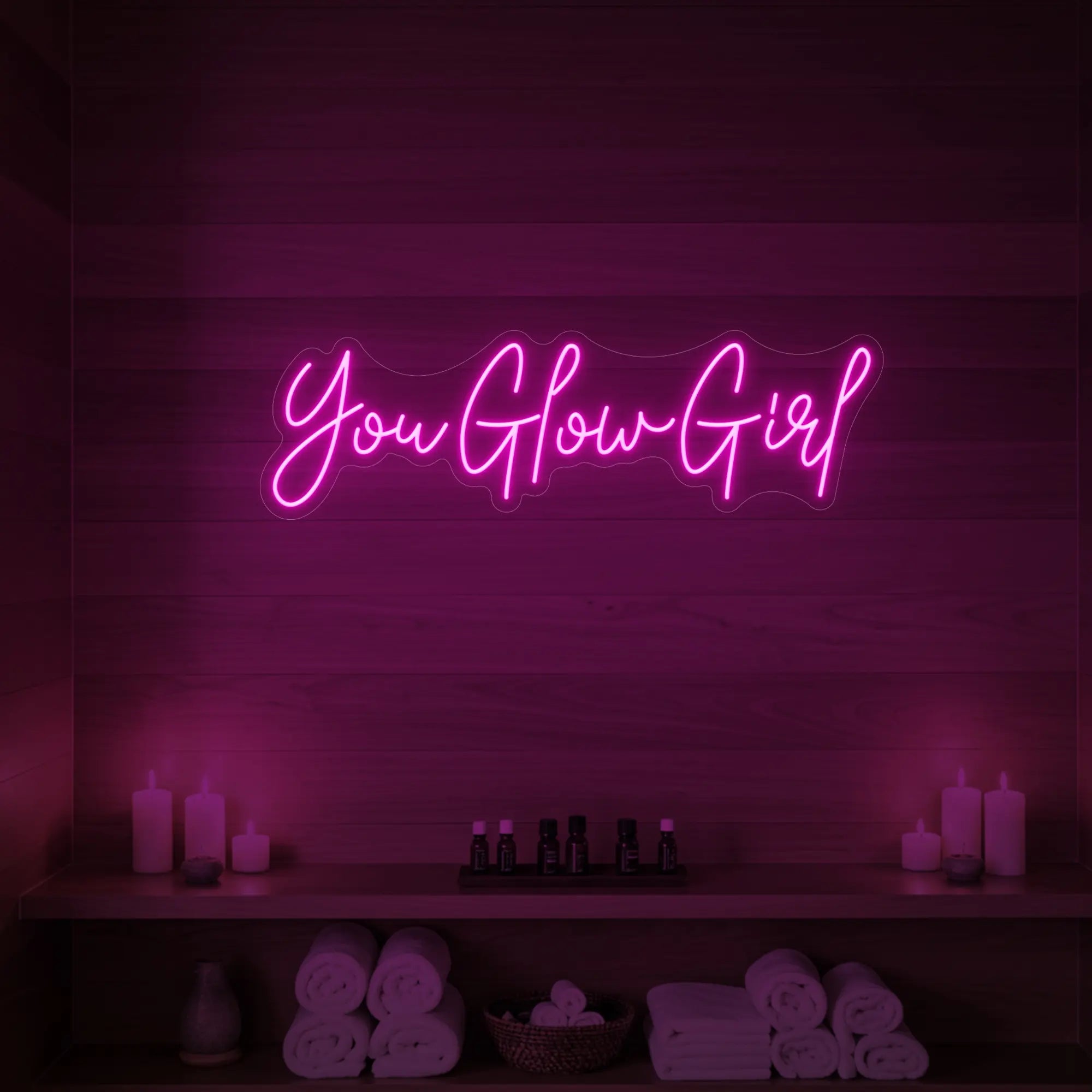 Photo of the 'You Glow Girl' neon sign glowing in light pink against a styled interior wall.