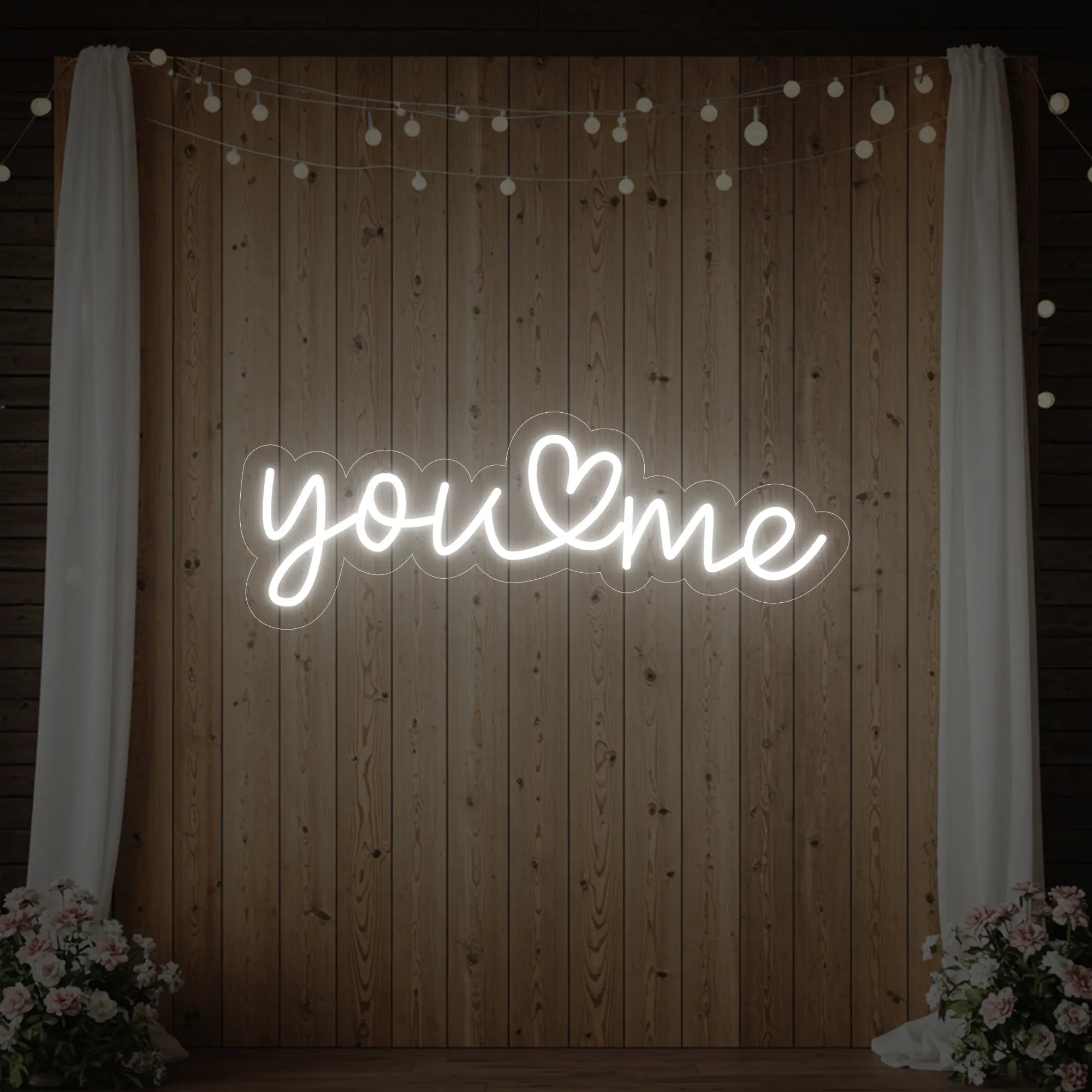 'You Heart Me' neon sign glowing in cool white against a styled interior wall.