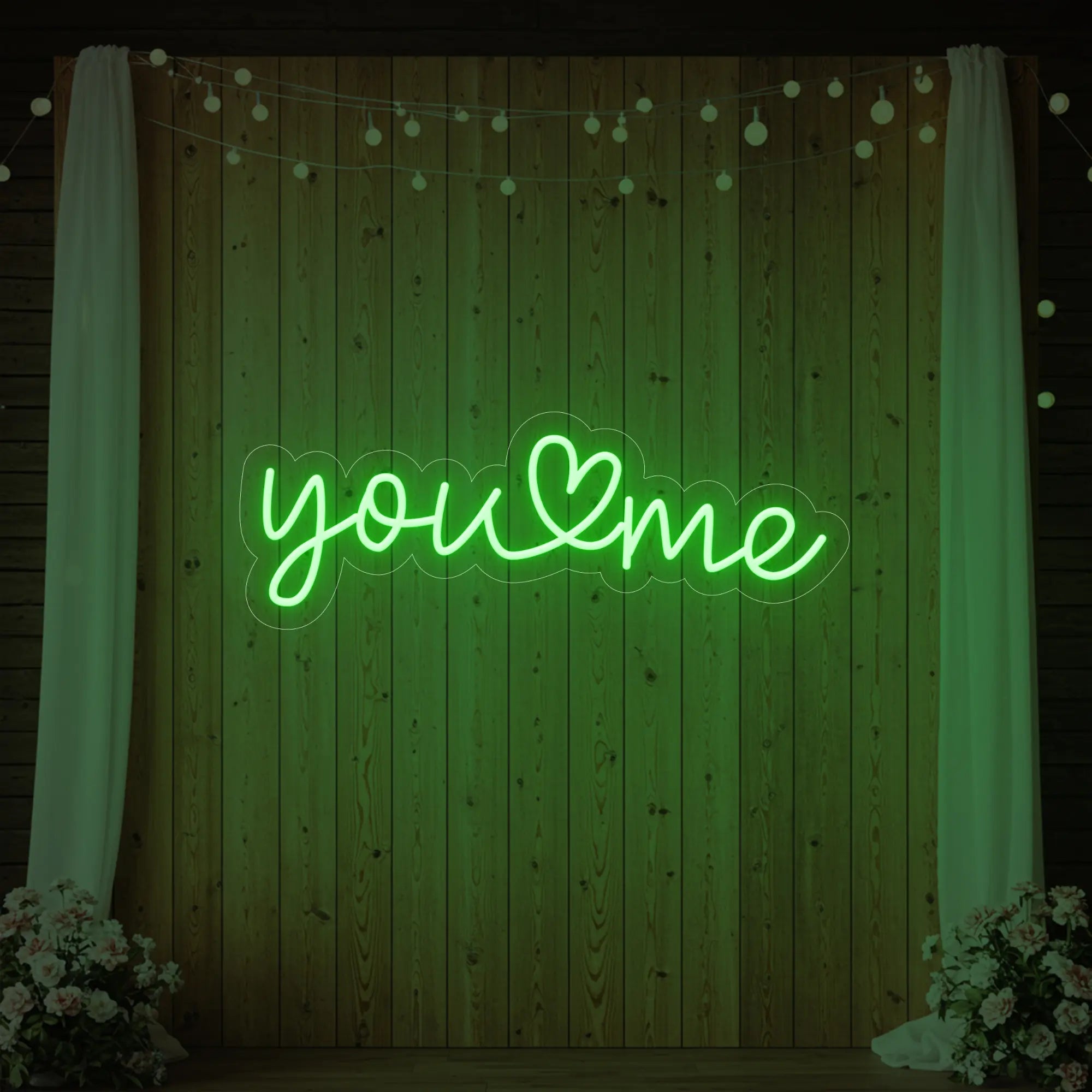'You Heart Me' neon sign glowing in green against a styled interior wall.