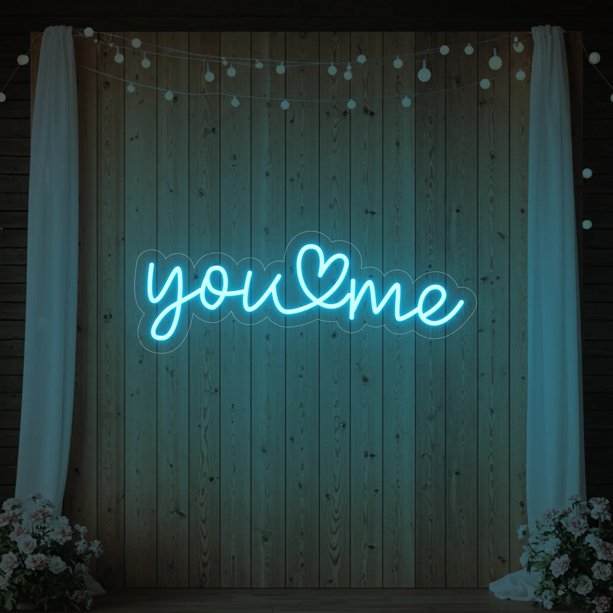 'You Heart Me' neon sign glowing in ice blue against a styled interior wall.