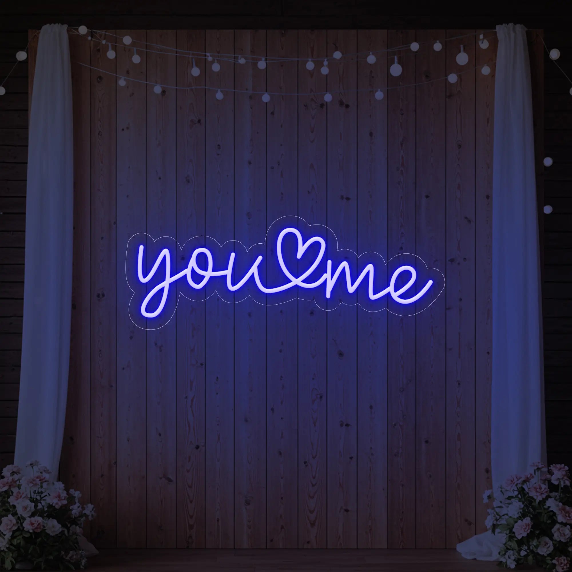 'You Heart Me' neon sign glowing in deep blue against a styled interior wall.
