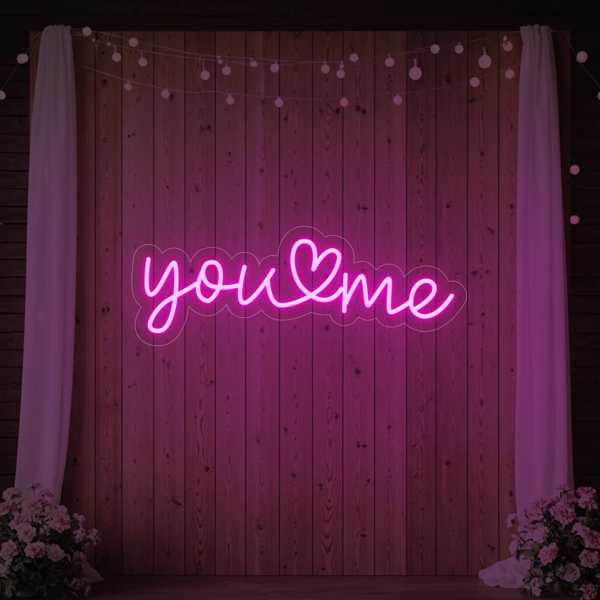 'You Heart Me' neon sign glowing in light pink against a styled interior wall.