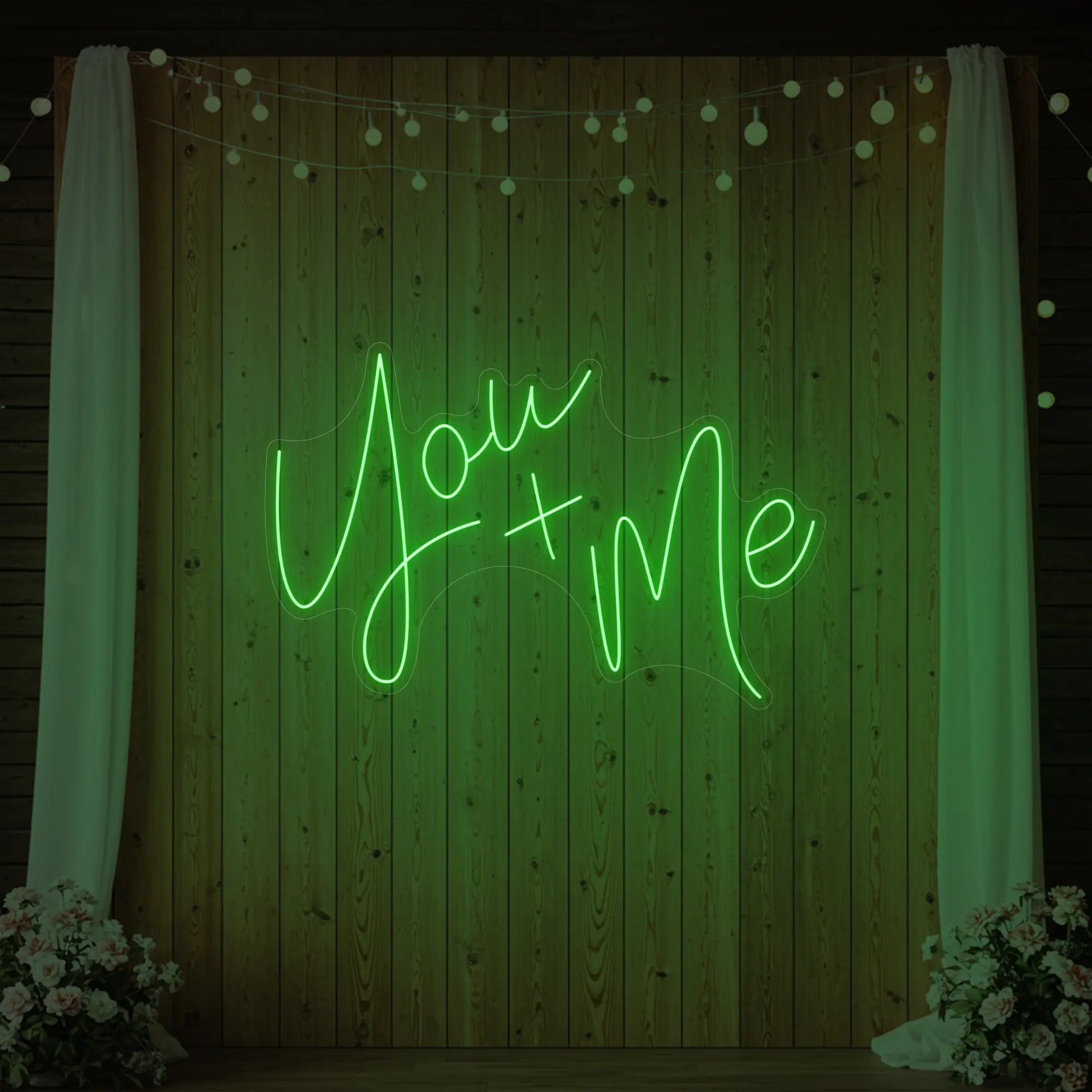 'You + Me' neon sign glowing in green against a styled interior wall.