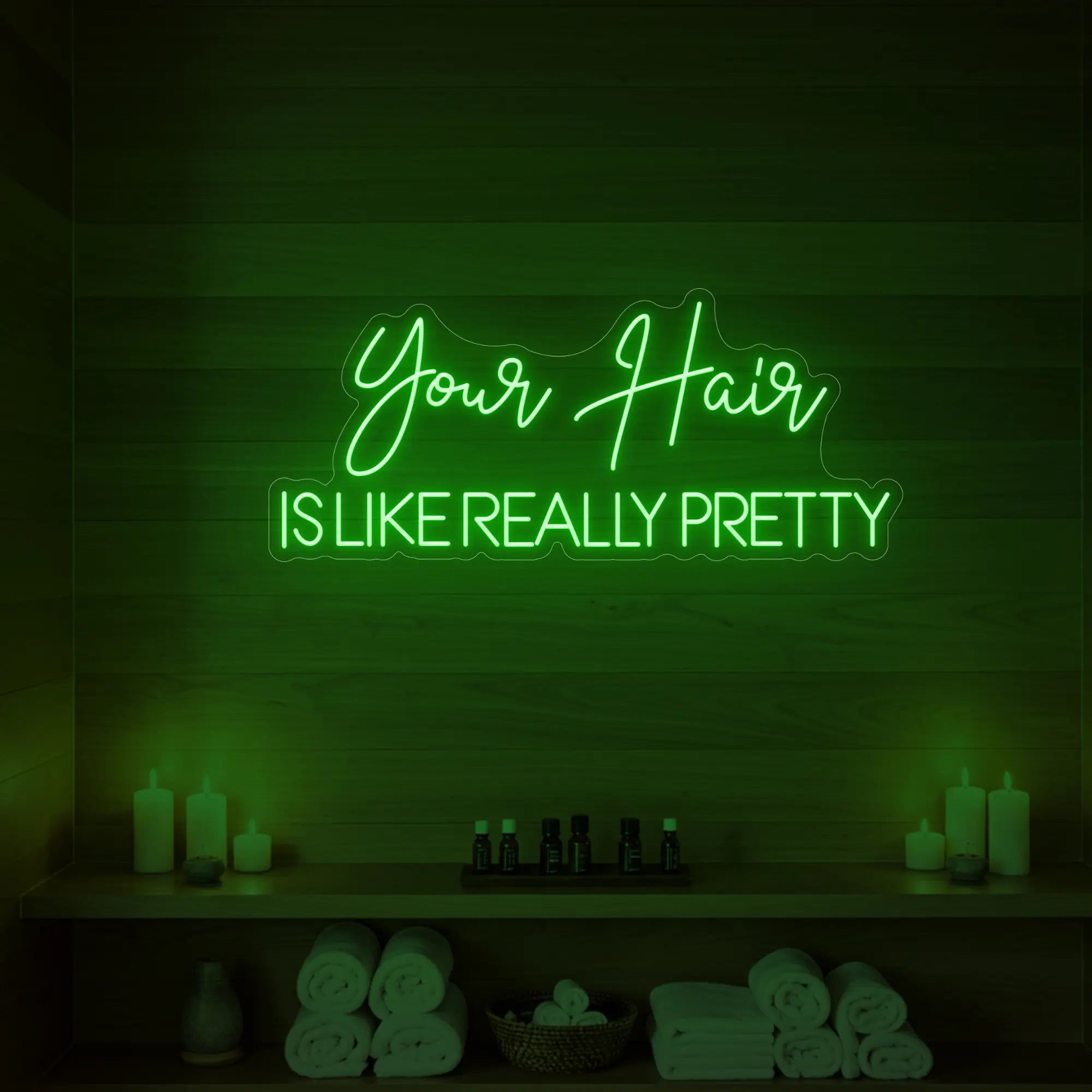 Photo of the 'Your Hair Is Like Really Pretty' neon sign glowing in green against a styled interior wall.