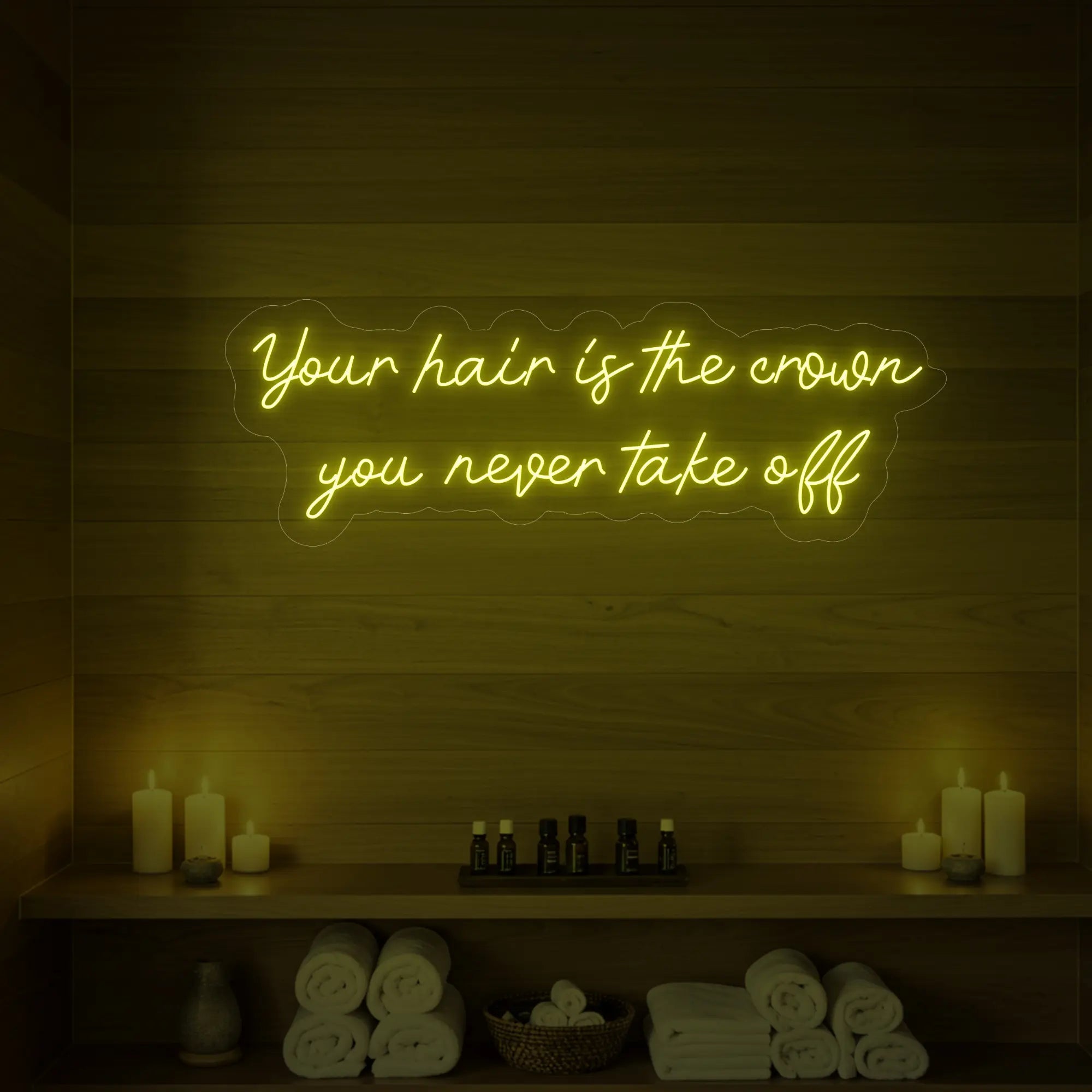 Photo of the 'Your Hair Is The Crown You Never Take Off' neon sign glowing in lemon yellow against a styled interior wall.