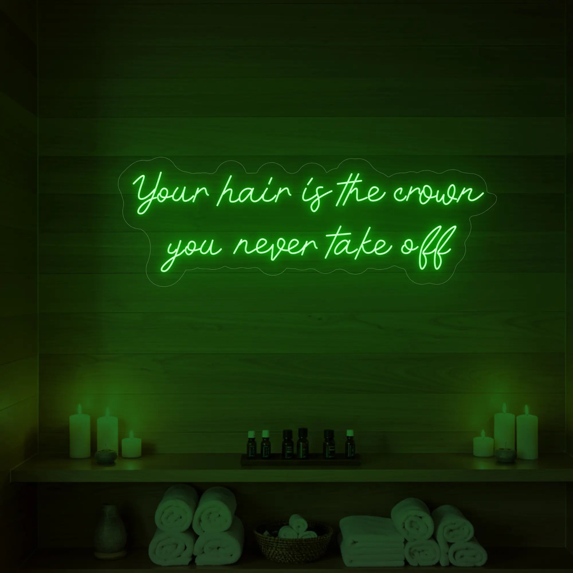 Photo of the 'Your Hair Is The Crown You Never Take Off' neon sign glowing in green against a styled interior wall.