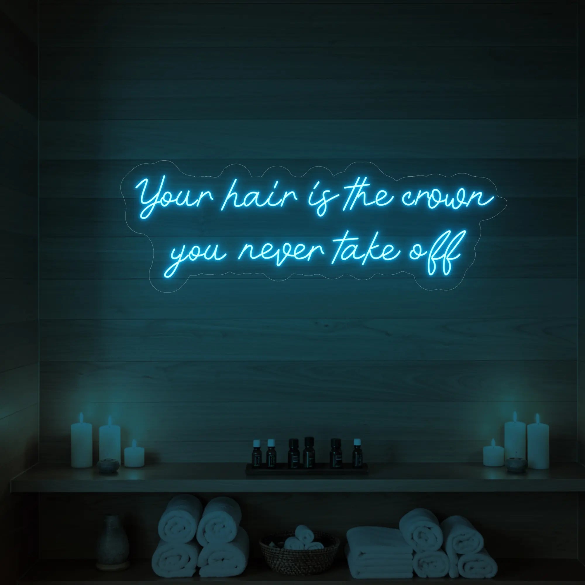 Photo of the 'Your Hair Is The Crown You Never Take Off' neon sign glowing in ice blue against a styled interior wall.