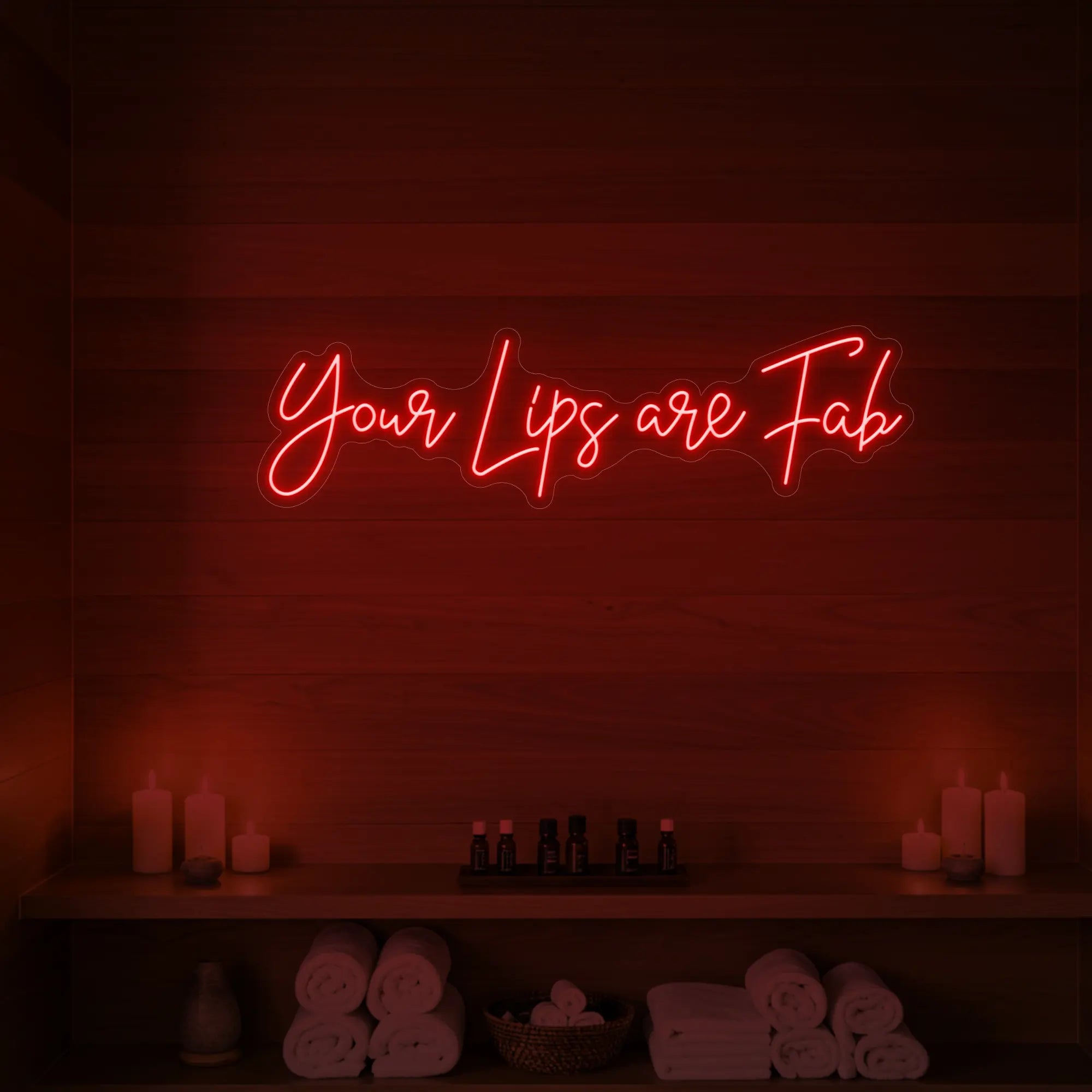 Photo of the 'Your Lips Are Fab' neon sign glowing in red against a styled interior wall.
