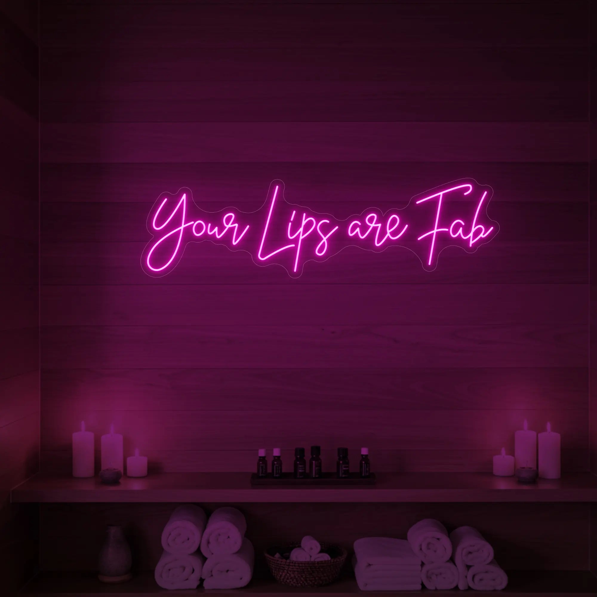 Photo of the 'Your Lips Are Fab' neon sign glowing in light pink against a styled interior wall.