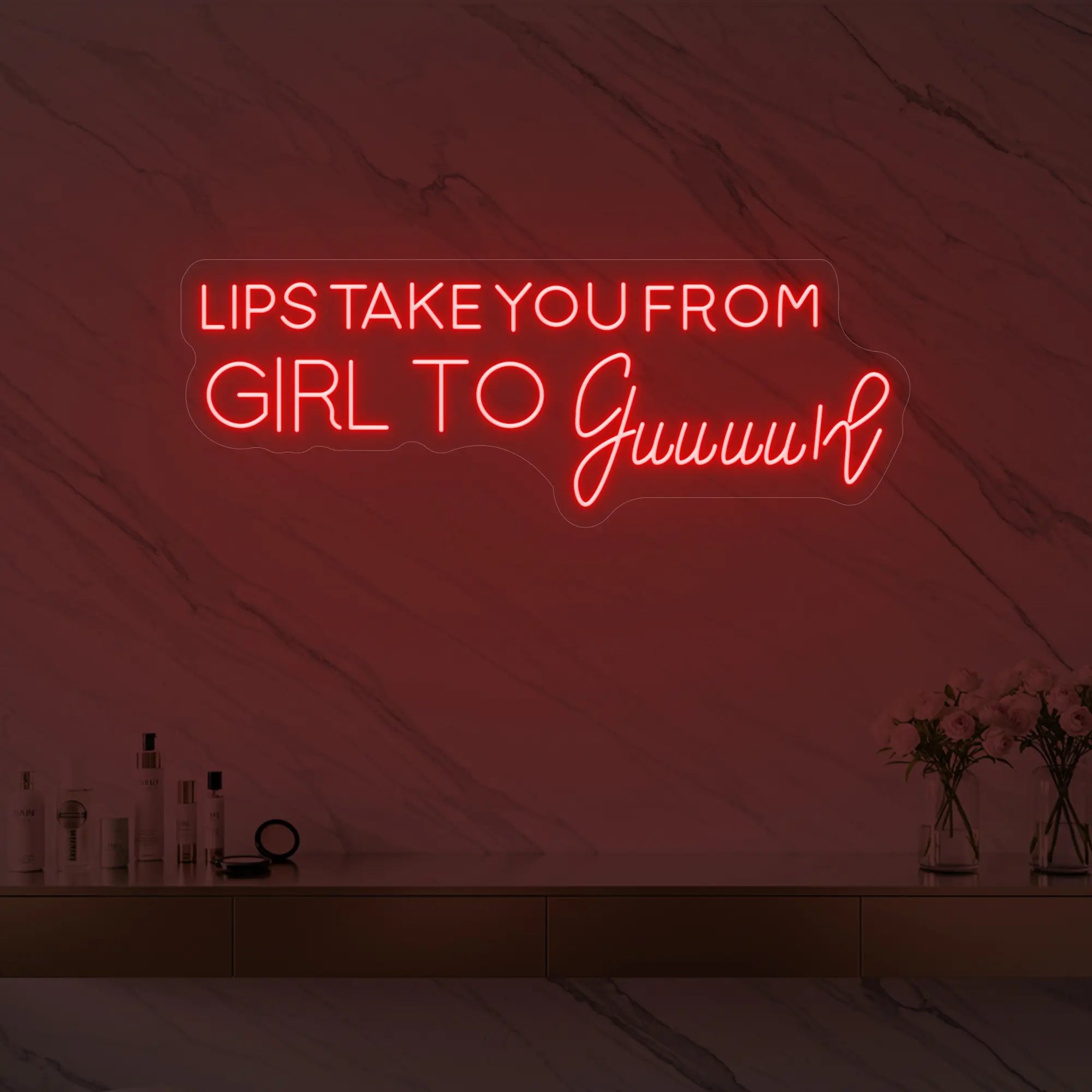 Photo of the 'LIPS TAKE YOU FROM GIRL TO Guuuurl' neon sign glowing in red against a styled interior wall.