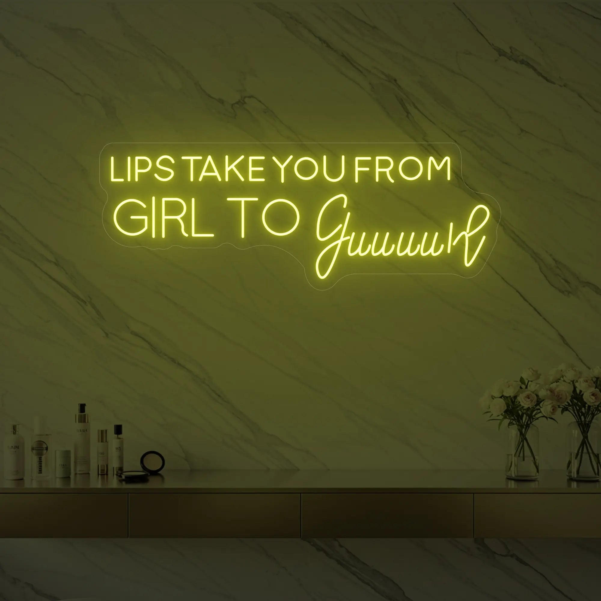 Photo of the 'LIPS TAKE YOU FROM GIRL TO Guuuurl' neon sign glowing in lemon yellow against a styled interior wall.