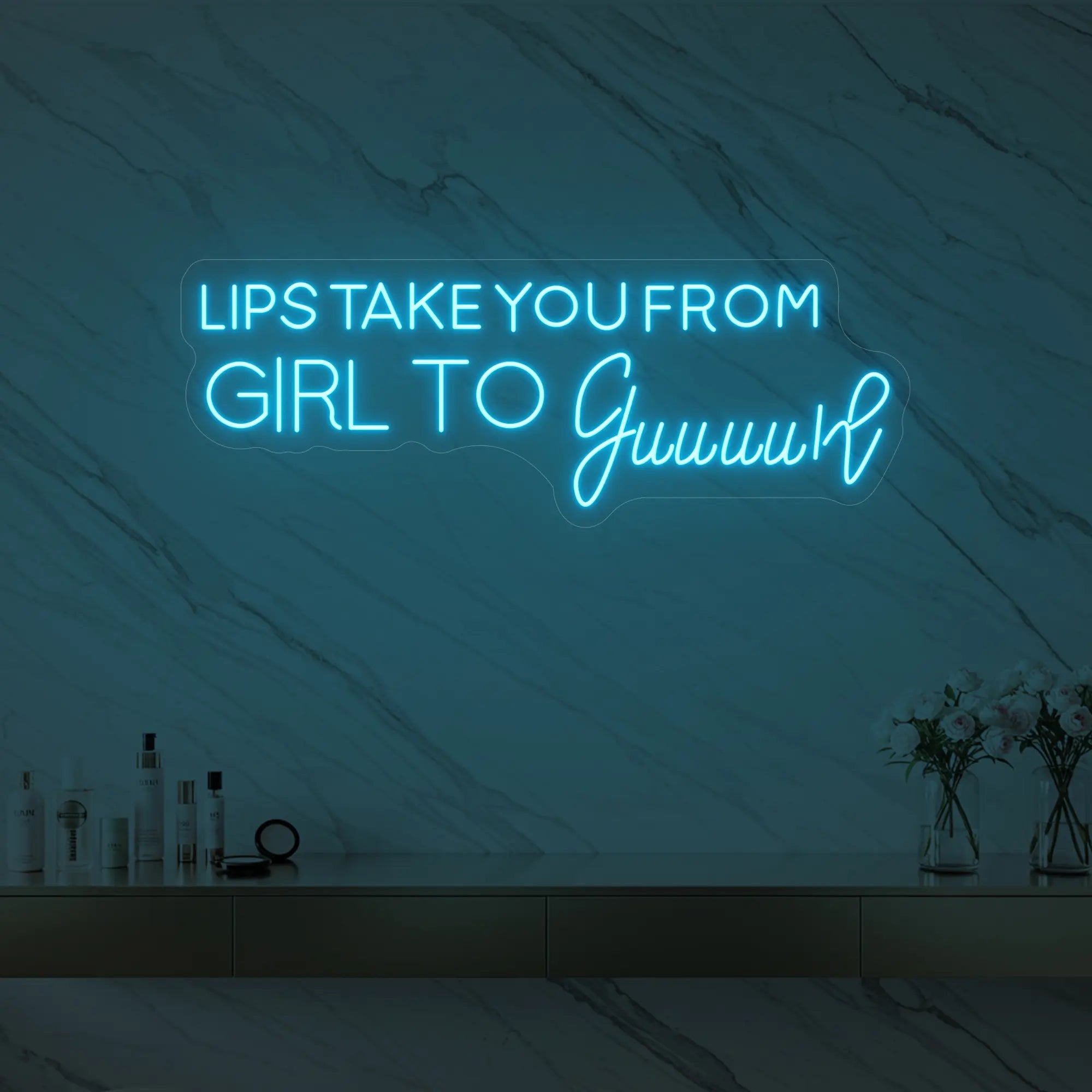 Photo of the 'LIPS TAKE YOU FROM GIRL TO Guuuurl' neon sign glowing in ice blue against a styled interior wall.