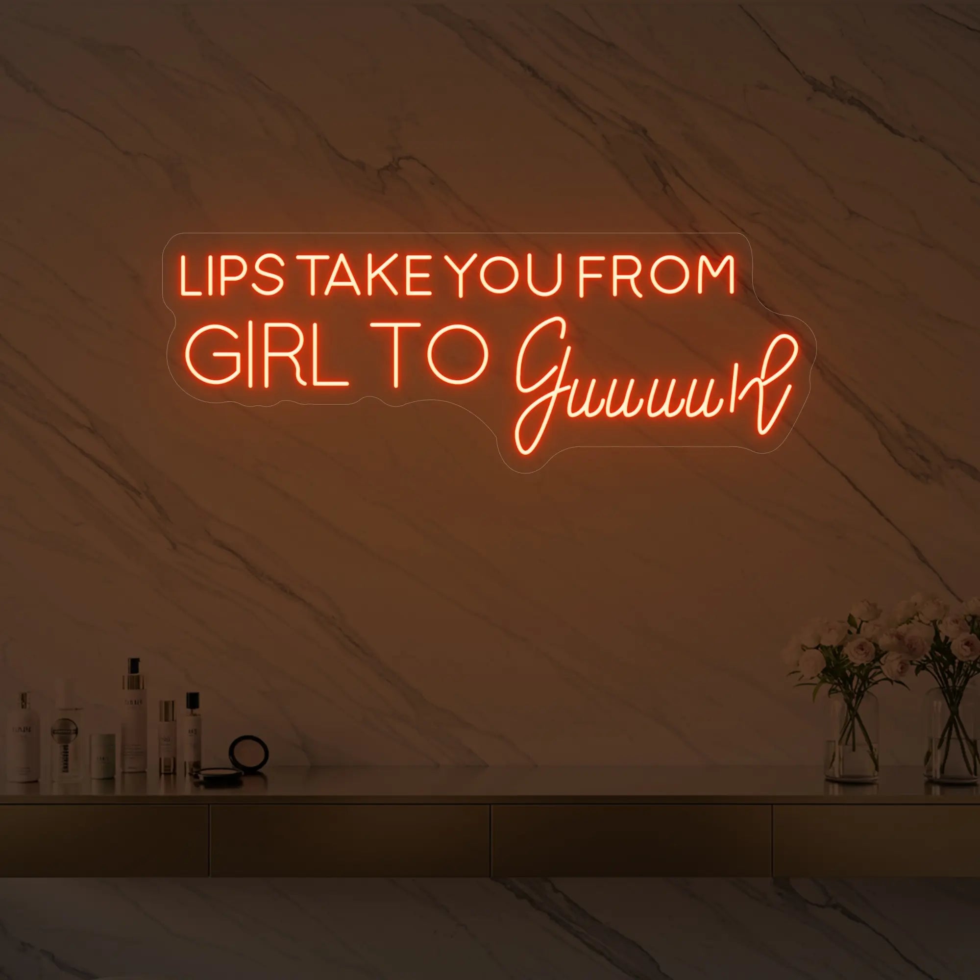 Photo of the 'LIPS TAKE YOU FROM GIRL TO Guuuurl' neon sign glowing in golden yellow against a styled interior wall.