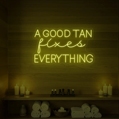 Photo of the 'A GOOD TAN fixes EVERYTHING' neon sign glowing in lemon yellow against a styled interior wall.