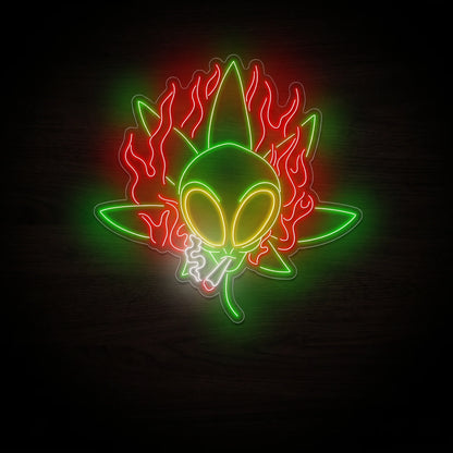 Green alien cannabis flame LED neon sign with yellow eyes, red flames, a cannabis leaf, smoking joint, white smoke, and clear acrylic backing.
