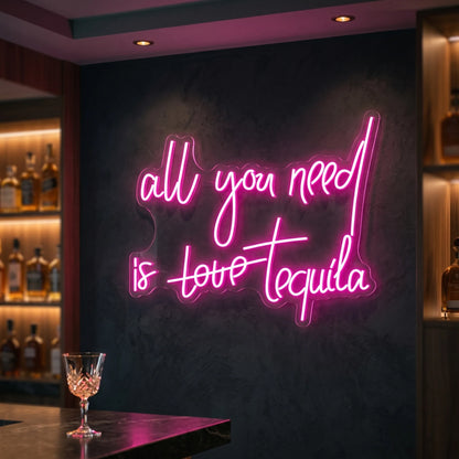 Photo of the 'All you need is tequila' neon sign glowing in deep pink against a styled interior wall.