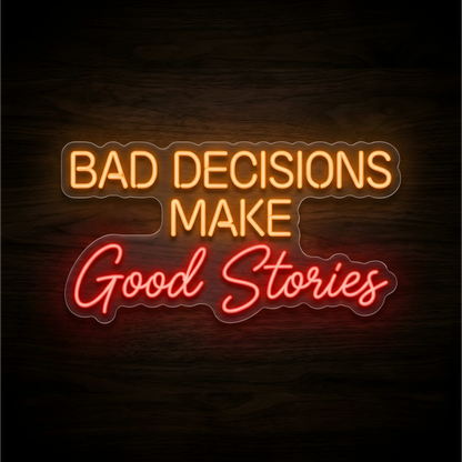 Bad Decisions Make Good Stories LED Neon Sign with orange uppercase lettering and red script lettering on clear acrylic against a dark wood background, suited to home bars and game rooms.