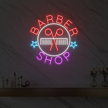 Photo of the 'Barber Shop' neon sign glowing in multi-color against a styled interior wall.