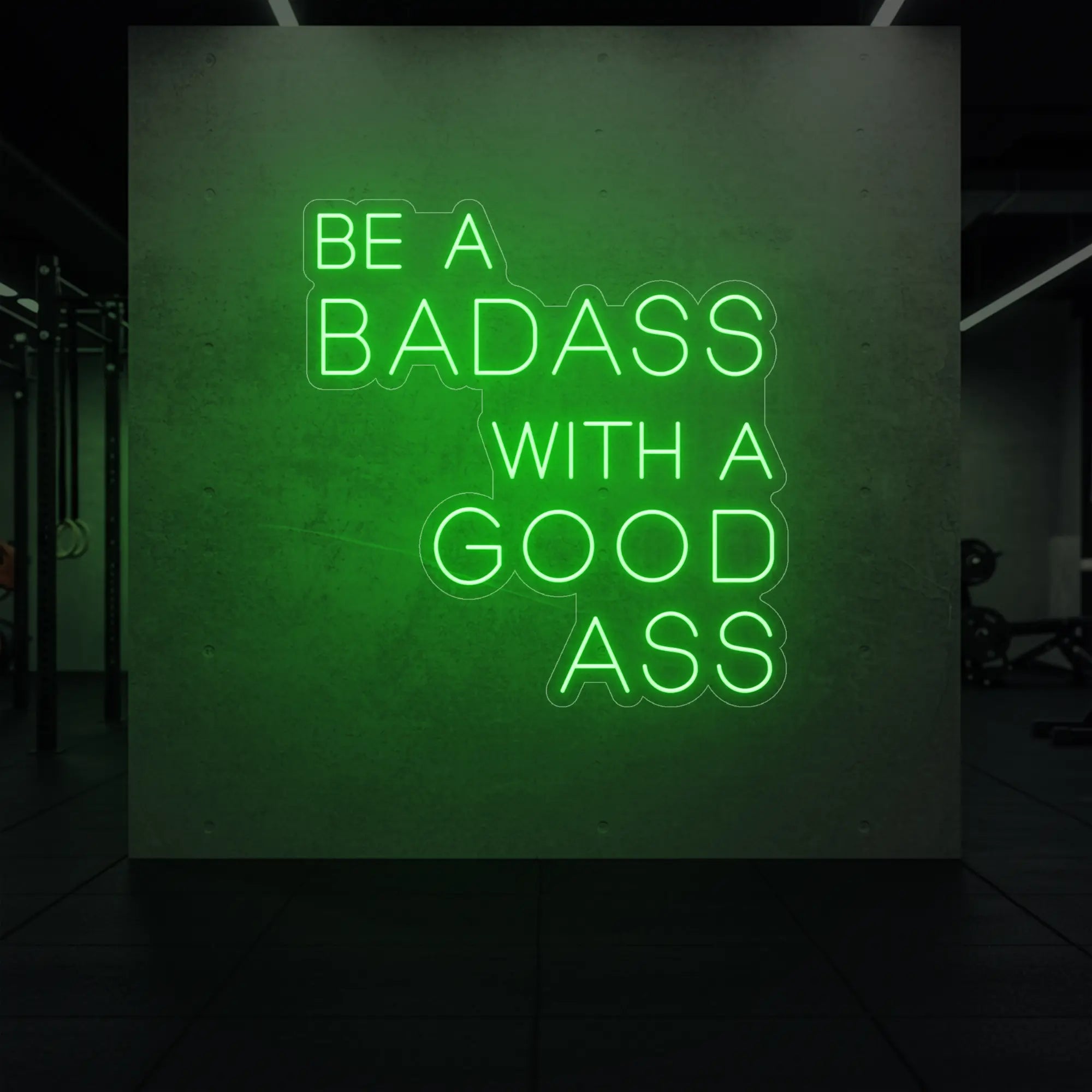 'Be a Badass With a Good Ass' neon sign glowing in green against a styled interior wall.