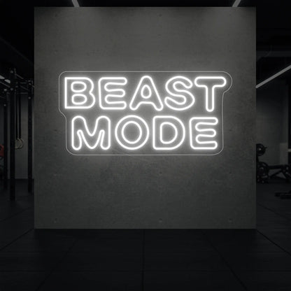 'Beast Mode' neon sign glowing in cool white against a styled interior wall.