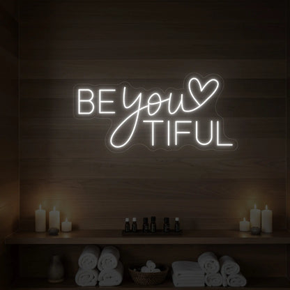 Photo of the 'BEYOUtiful' neon sign glowing in cool white against a styled interior wall.