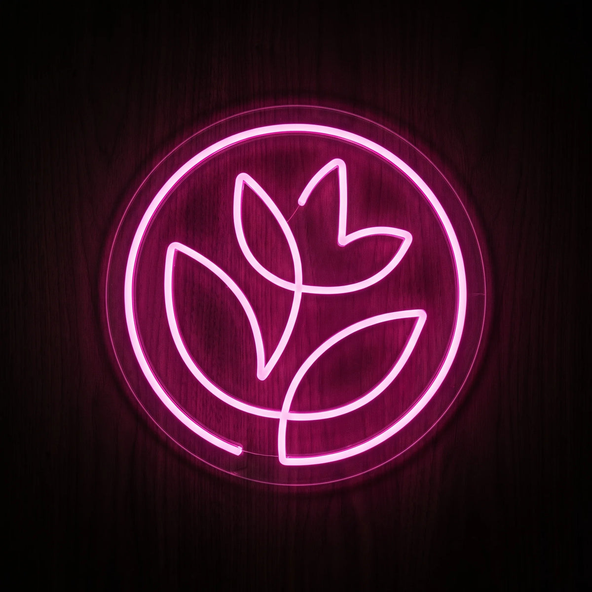 Pink botanical circle LED neon sign with flower and leaf design on clear acrylic backing.