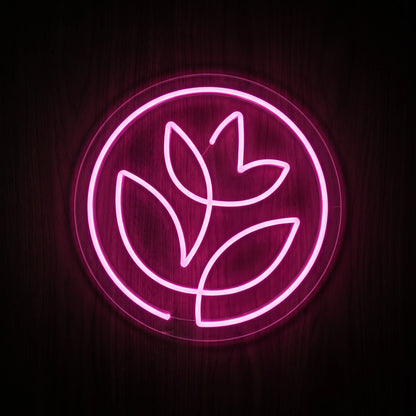 Pink botanical circle LED neon sign with flower and leaf design on clear acrylic backing.