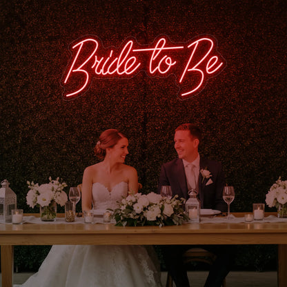Photo of the 'Bride To Be' neon sign glowing in red against a styled interior wall.