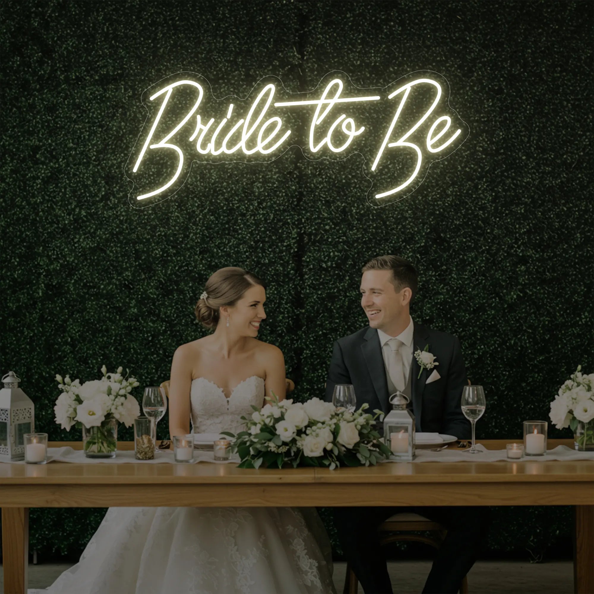 Photo of the 'Bride To Be' neon sign glowing in warm white against a styled interior wall.