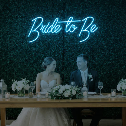 Photo of the 'Bride To Be' neon sign glowing in ice blue against a styled interior wall.