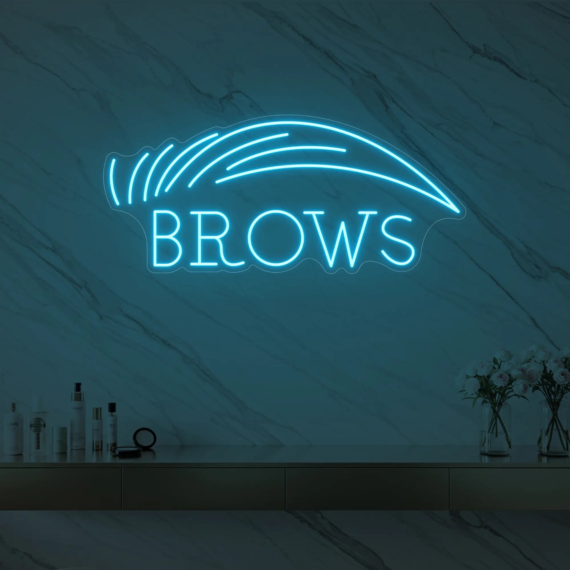 Photo of the 'BROWS' neon sign with an eyebrow graphic glowing in ice blue against a styled interior wall.