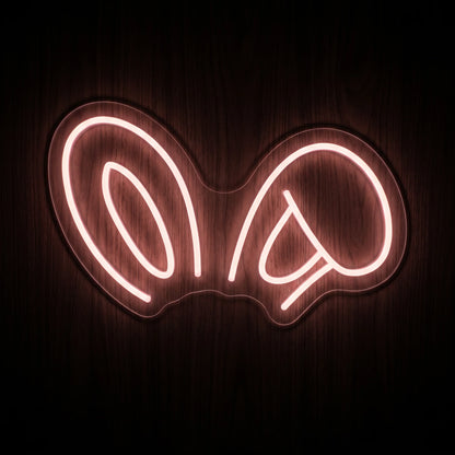 Bunny Headband LED neon sign featuring oversized bunny ear outlines illuminated in a soft pink glow on clear acrylic backing.