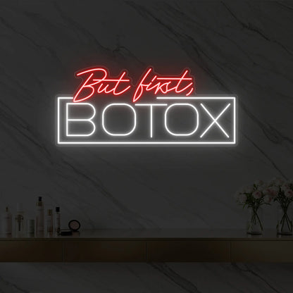Photo of the 'But first, BOTOX' neon sign glowing in red against a styled interior wall.