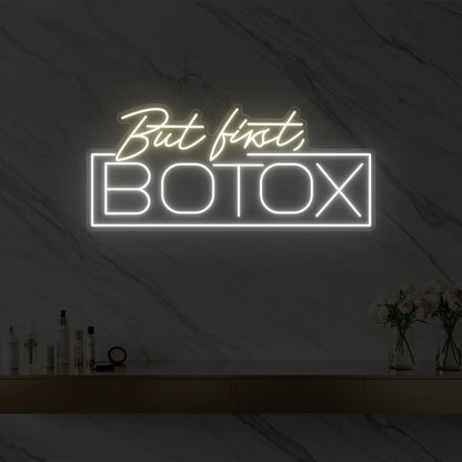 Photo of the 'But first, BOTOX' neon sign glowing in warm white against a styled interior wall.